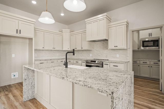 kitchen with electric stove, sink, hanging light fixtures, light hardwood / wood-style floors, and built in microwave