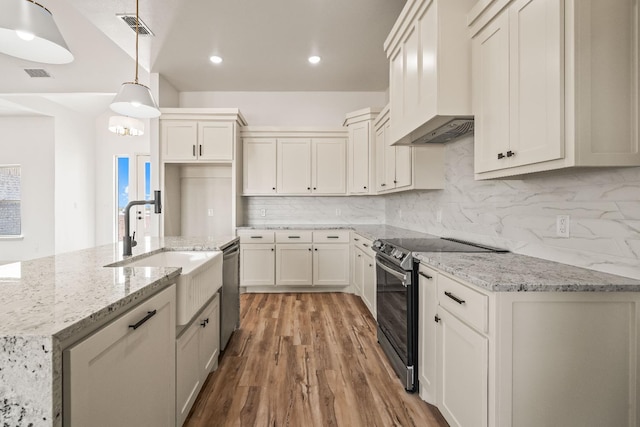 kitchen with pendant lighting, premium range hood, appliances with stainless steel finishes, light stone countertops, and white cabinets