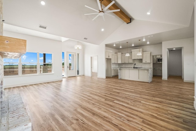 unfurnished living room with sink, beam ceiling, high vaulted ceiling, and light hardwood / wood-style flooring