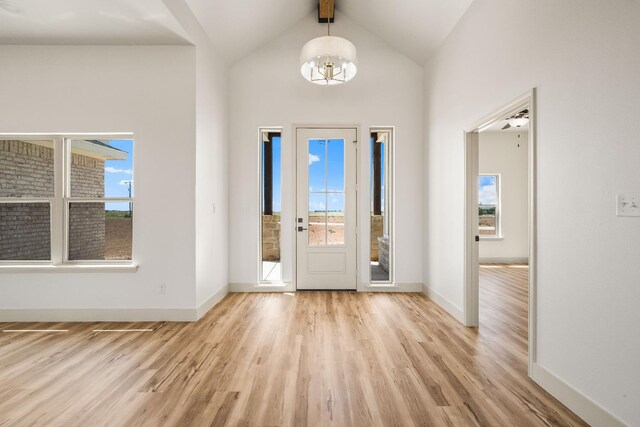 entryway featuring a chandelier, lofted ceiling with beams, and light wood-type flooring