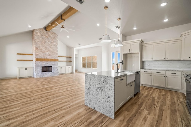 kitchen featuring sink, a center island with sink, a large fireplace, dishwasher, and pendant lighting