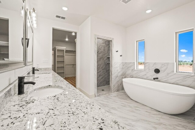 bathroom with independent shower and bath, vanity, and tile walls