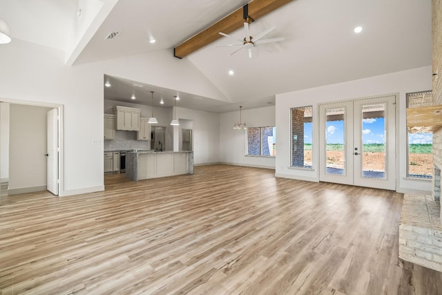 unfurnished living room with beam ceiling, plenty of natural light, high vaulted ceiling, and light wood-type flooring