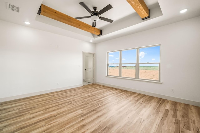 spare room with beam ceiling, a raised ceiling, ceiling fan, and light wood-type flooring