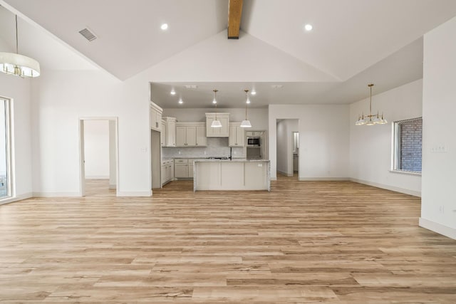 kitchen featuring backsplash, light hardwood / wood-style floors, a center island with sink, decorative light fixtures, and a chandelier