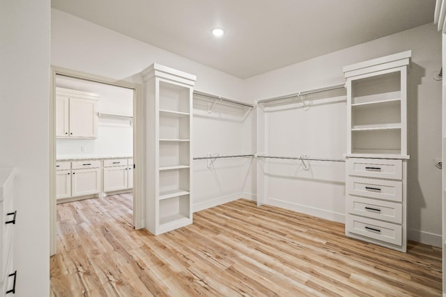 walk in closet with light hardwood / wood-style floors