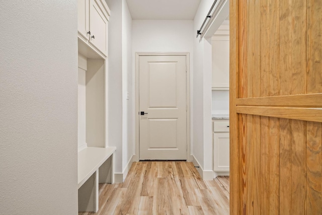 mudroom with a barn door and light wood-type flooring