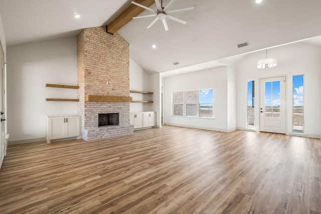 unfurnished living room with high vaulted ceiling, beamed ceiling, ceiling fan, a brick fireplace, and light wood-type flooring