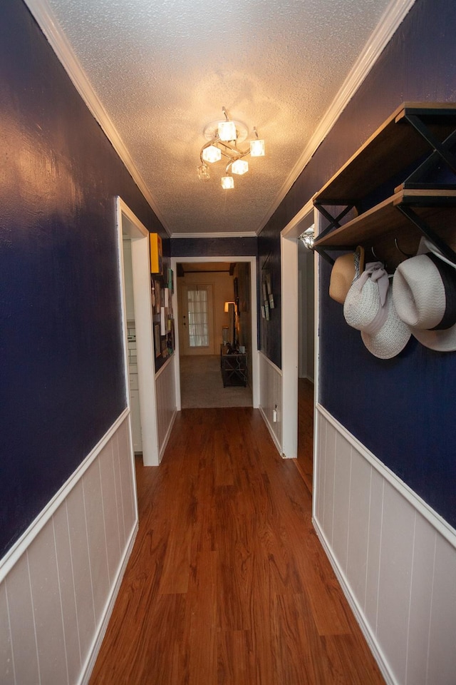 hallway with ornamental molding, wood-type flooring, and a textured ceiling