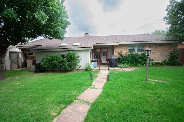 ranch-style house featuring a front lawn and a shed