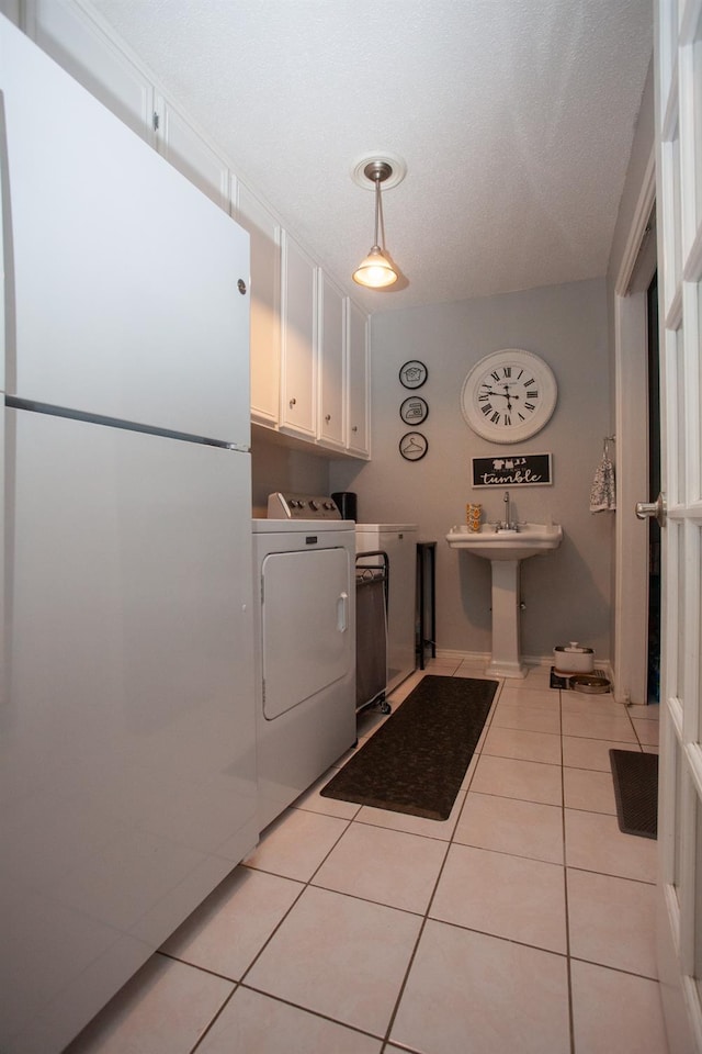 laundry area featuring cabinets, separate washer and dryer, sink, and light tile patterned floors