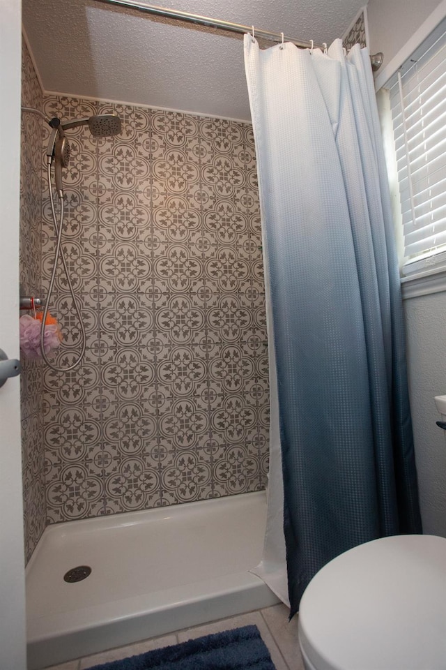 bathroom with curtained shower, a textured ceiling, and toilet