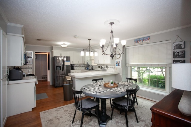 dining space with crown molding, sink, dark hardwood / wood-style floors, and an inviting chandelier