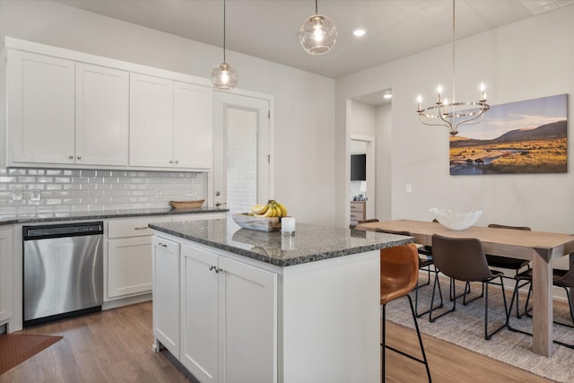 kitchen featuring tasteful backsplash, white cabinets, an inviting chandelier, dishwasher, and wood finished floors
