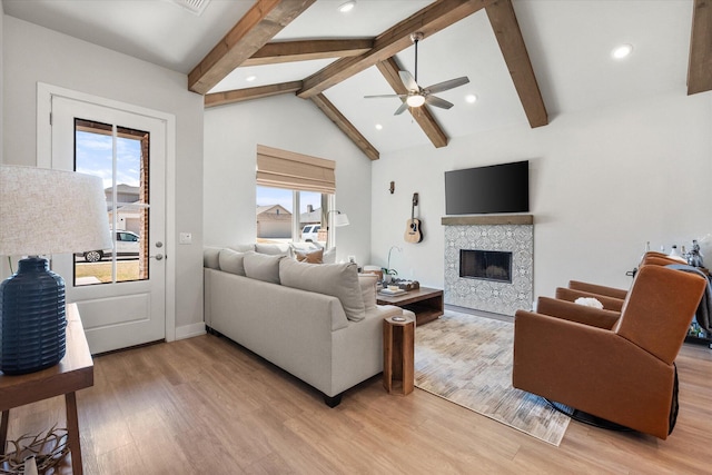 living area with plenty of natural light, light wood-type flooring, a ceiling fan, and a tiled fireplace