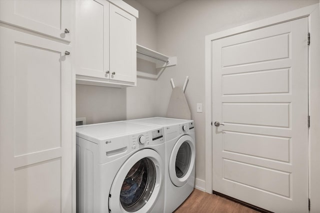 clothes washing area with cabinet space, independent washer and dryer, wood finished floors, and baseboards