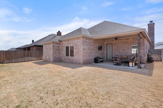 rear view of house with a chimney, a fenced backyard, a yard, ceiling fan, and a patio