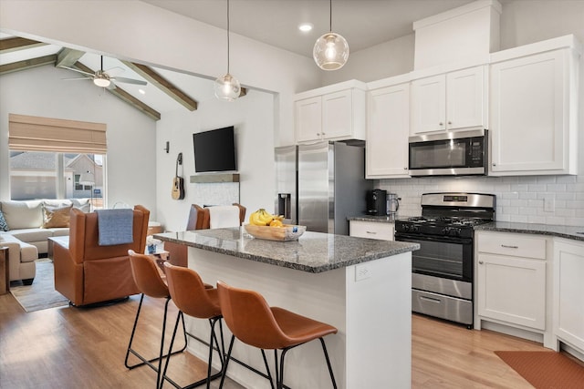 kitchen with light wood-style floors, a ceiling fan, backsplash, appliances with stainless steel finishes, and open floor plan
