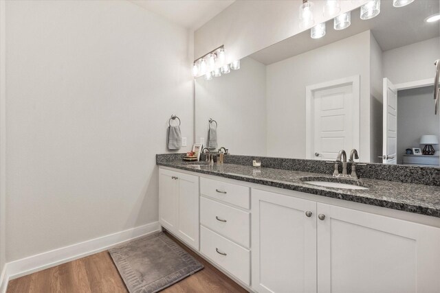 full bathroom with a sink, wood finished floors, and baseboards