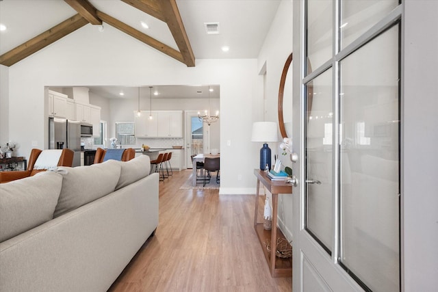 living area with light wood-style flooring, visible vents, baseboards, beam ceiling, and recessed lighting