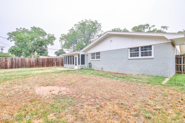 4815 15th St, Lubbock, TX 79416 - back of house featuring a sunroom, brick siding, and a fenced backyard