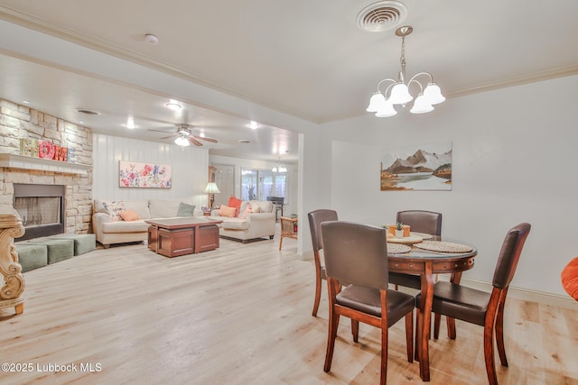 4815 15th St, Lubbock, TX 79416 - dining space with light wood-type flooring, a stone fireplace, crown molding, a chandelier, and a ceiling fan