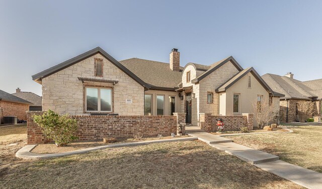 4005 127th St, Lubbock, TX 79423 - french country style house featuring stone siding, a chimney, and a front yard