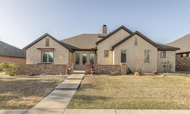 4005 127th St, Lubbock, TX 79423 - french country inspired facade featuring stone siding, a chimney, a front lawn, and french doors