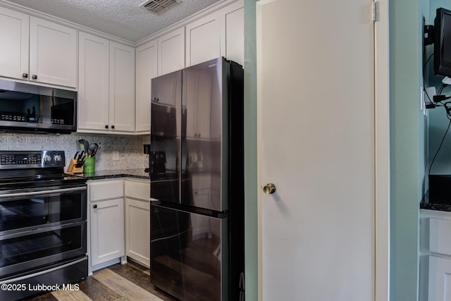 8609 Kenosha Dr, Lubbock, TX 79423 - kitchen with freestanding refrigerator, stainless steel microwave, double oven range, white cabinetry, and backsplash