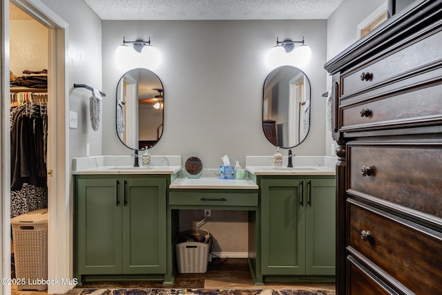8609 Kenosha Dr, Lubbock, TX 79423 - bathroom featuring double vanity, a textured ceiling, ceiling fan, a spacious closet, and wood finished floors
