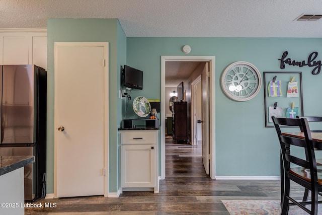 8609 Kenosha Dr, Lubbock, TX 79423 - kitchen featuring freestanding refrigerator, a textured ceiling, dark wood-type flooring, white cabinets, and baseboards