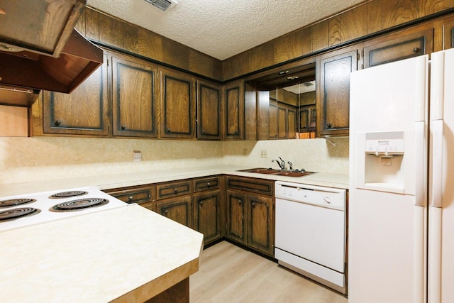 kitchen with range hood, sink, white appliances, light hardwood / wood-style floors, and a textured ceiling