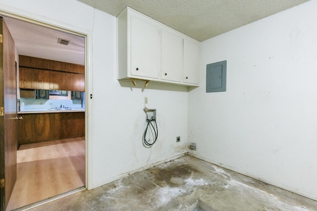 washroom featuring cabinets, a textured ceiling, electric panel, hookup for a washing machine, and hookup for an electric dryer