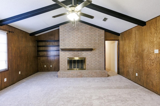 unfurnished living room featuring lofted ceiling with beams, a fireplace, wooden walls, and light colored carpet