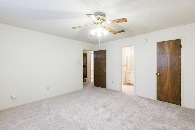 unfurnished bedroom with ceiling fan, ensuite bath, and light carpet