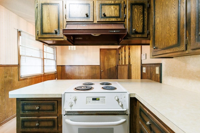 kitchen with wood walls, exhaust hood, and white range with electric stovetop