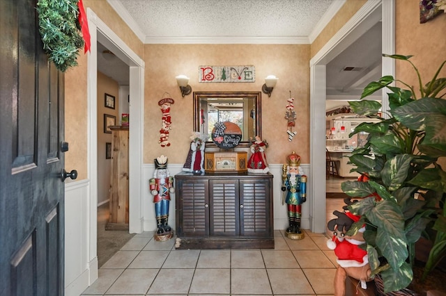 tiled entryway with crown molding and a textured ceiling