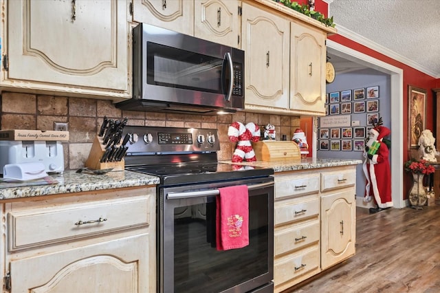 kitchen with appliances with stainless steel finishes, backsplash, dark hardwood / wood-style flooring, ornamental molding, and a textured ceiling