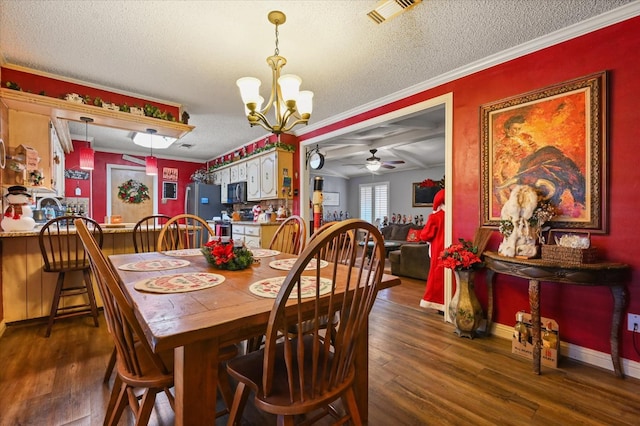 dining area with ornamental molding, dark wood-type flooring, ceiling fan with notable chandelier, and a textured ceiling