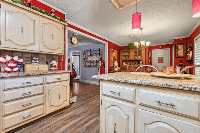 kitchen with crown molding, cream cabinets, and decorative light fixtures