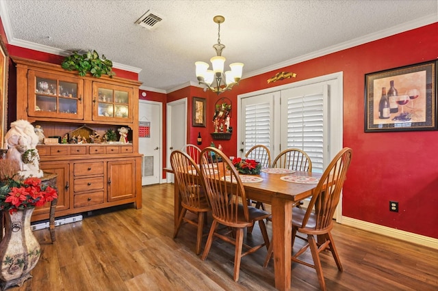 dining room with a notable chandelier, crown molding, wood-type flooring, and a textured ceiling