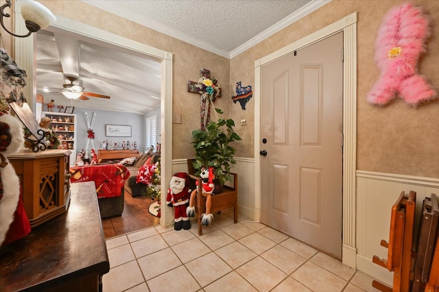 tiled entrance foyer with ornamental molding, ceiling fan, and a textured ceiling