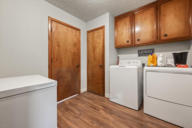 washroom featuring dark wood-type flooring, cabinets, washer and dryer, and a textured ceiling