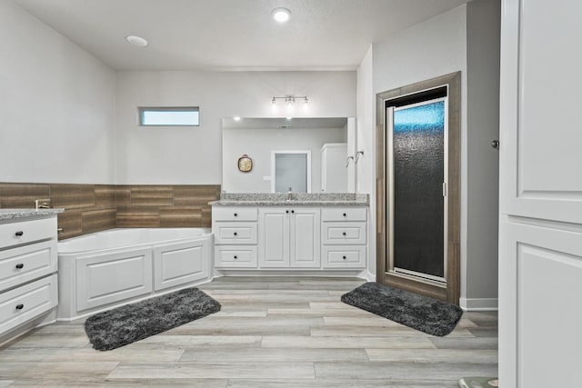 bathroom featuring hardwood / wood-style flooring, vanity, and plus walk in shower