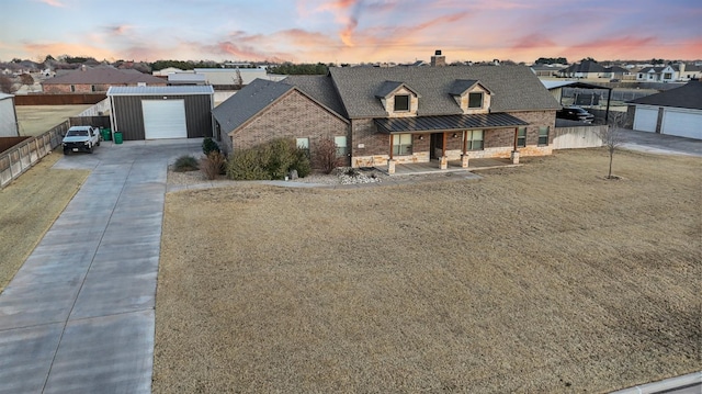 view of front of home with an outbuilding, a porch, a garage, and a yard