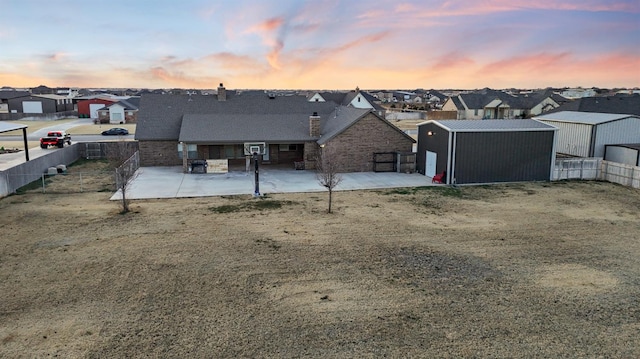 back house at dusk featuring a yard and a patio area