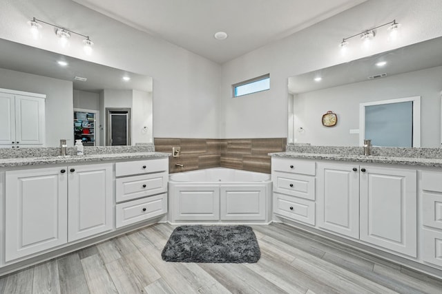 bathroom featuring hardwood / wood-style flooring, a tub to relax in, and vanity