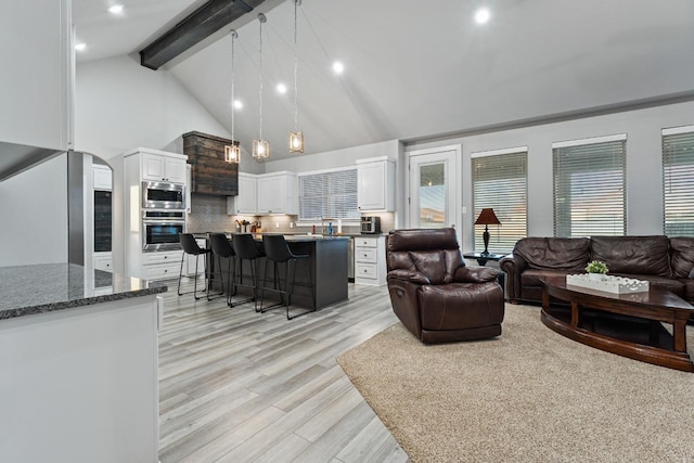 living room featuring beam ceiling, high vaulted ceiling, and light hardwood / wood-style flooring