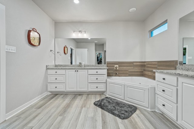 bathroom with vanity, a tub to relax in, and hardwood / wood-style flooring