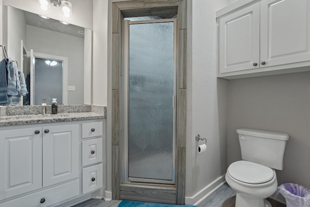 bathroom featuring vanity, hardwood / wood-style floors, an enclosed shower, and toilet